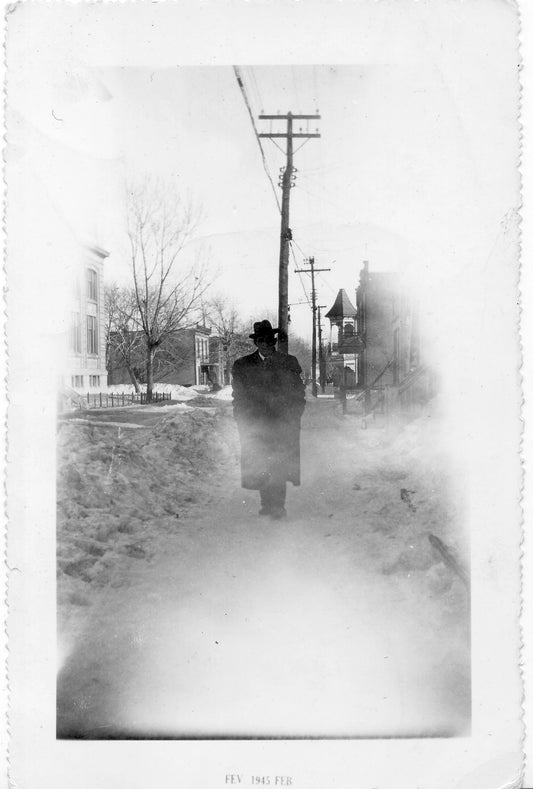 Homme marchant sur un trottoir enneigé