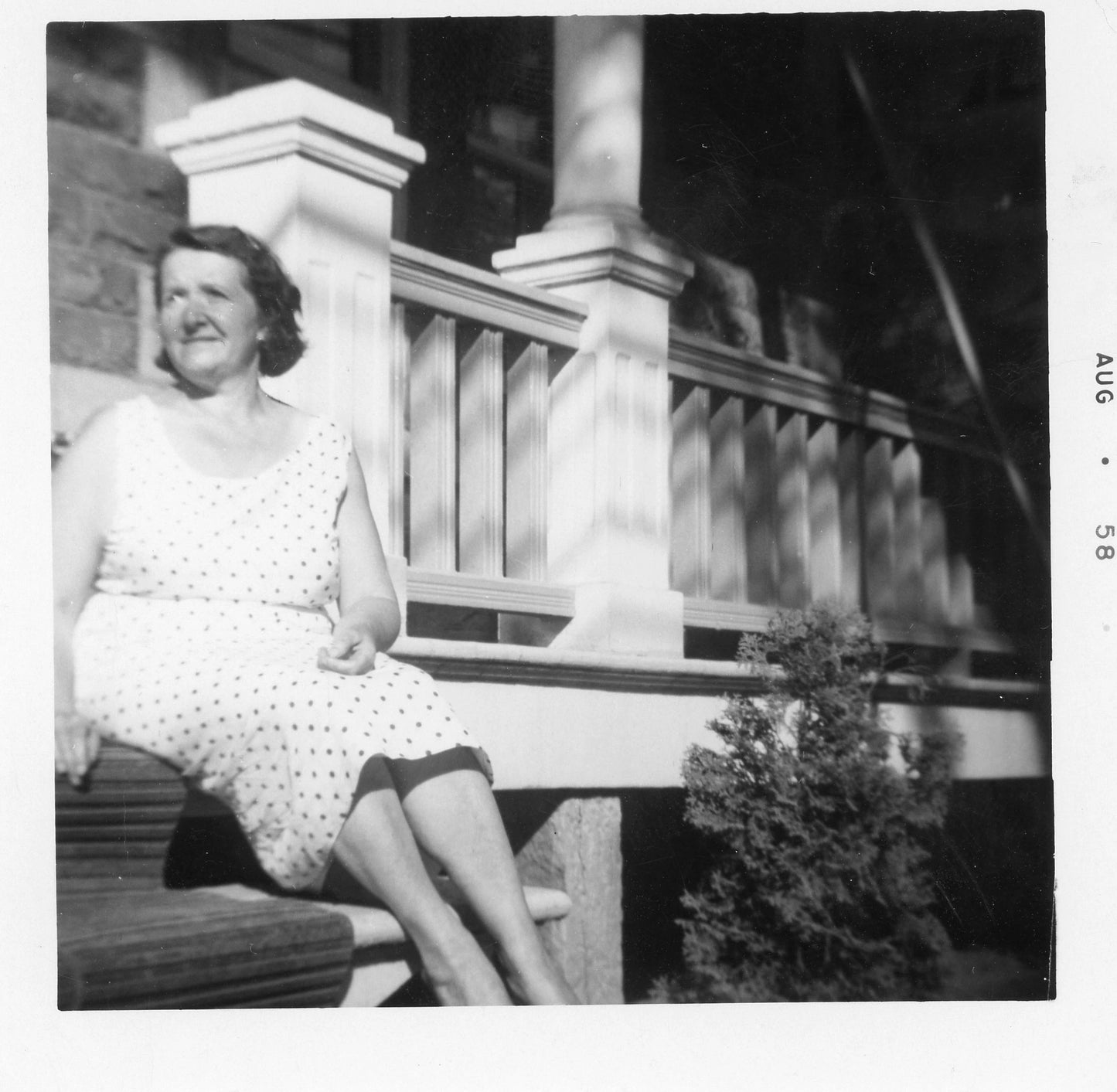 Mère assise devant la maison familiale