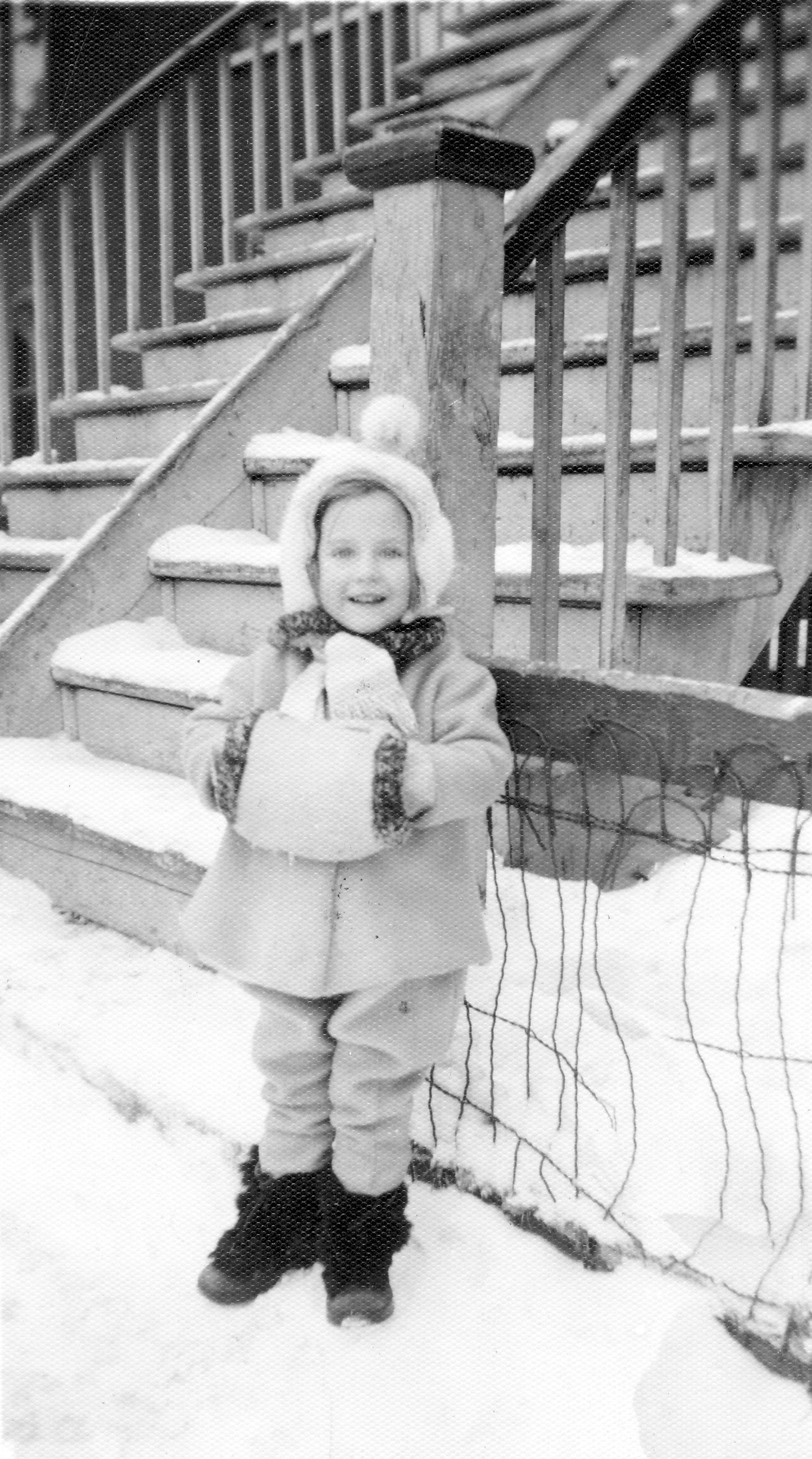 Un enfant en hiver devant sa maison