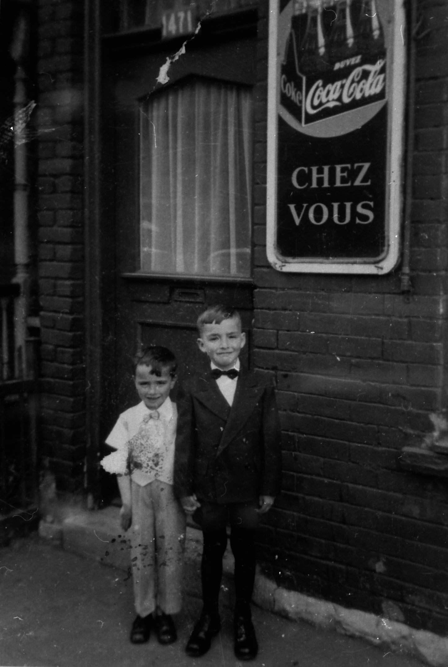 Portrait de deux enfants devant une affiche Coca-Cola