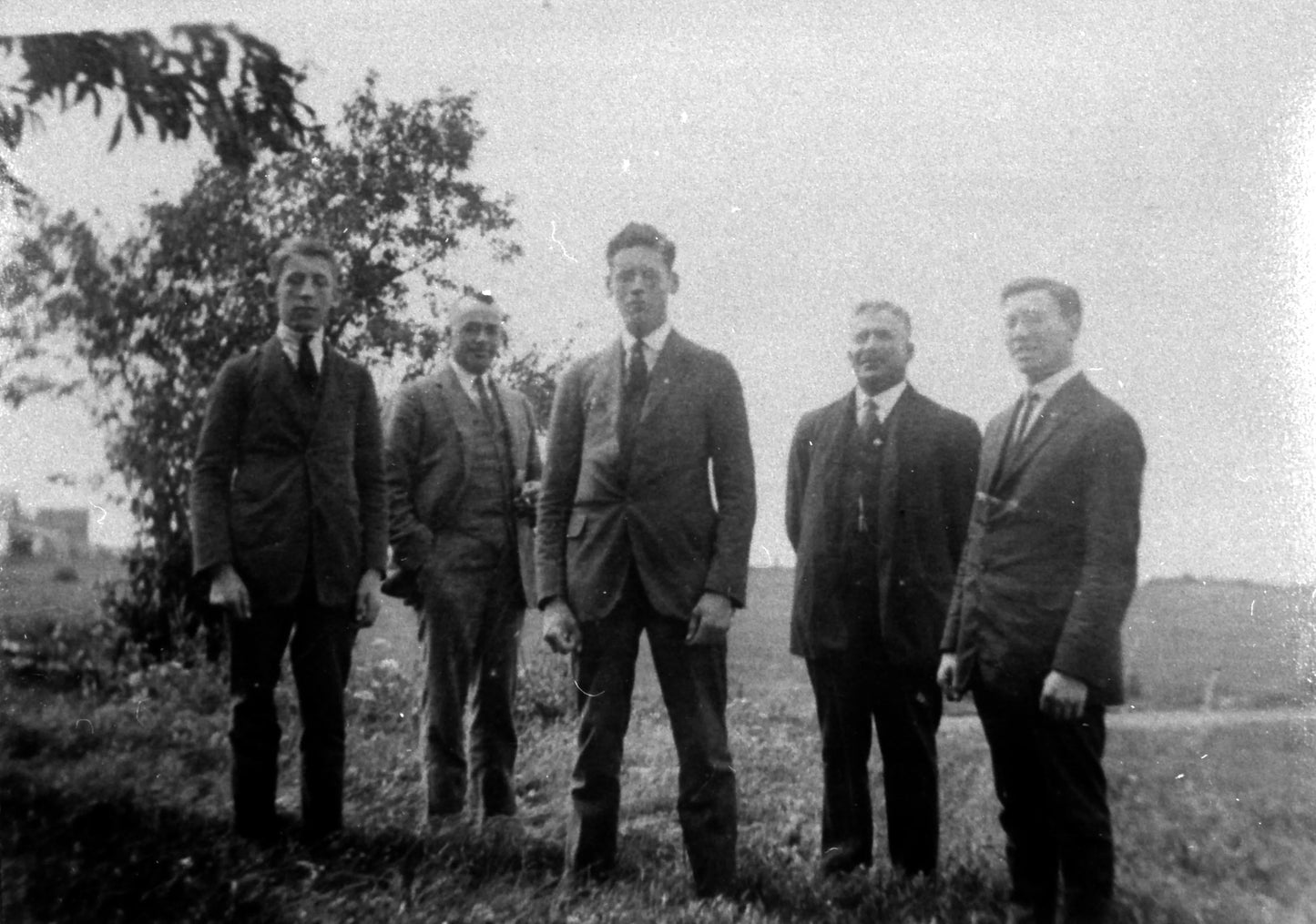 Iréné Sicard, M. Boucher, Wilfrid, Arthur et Hervé Sicard debout sur l'herbe près d'un arbre