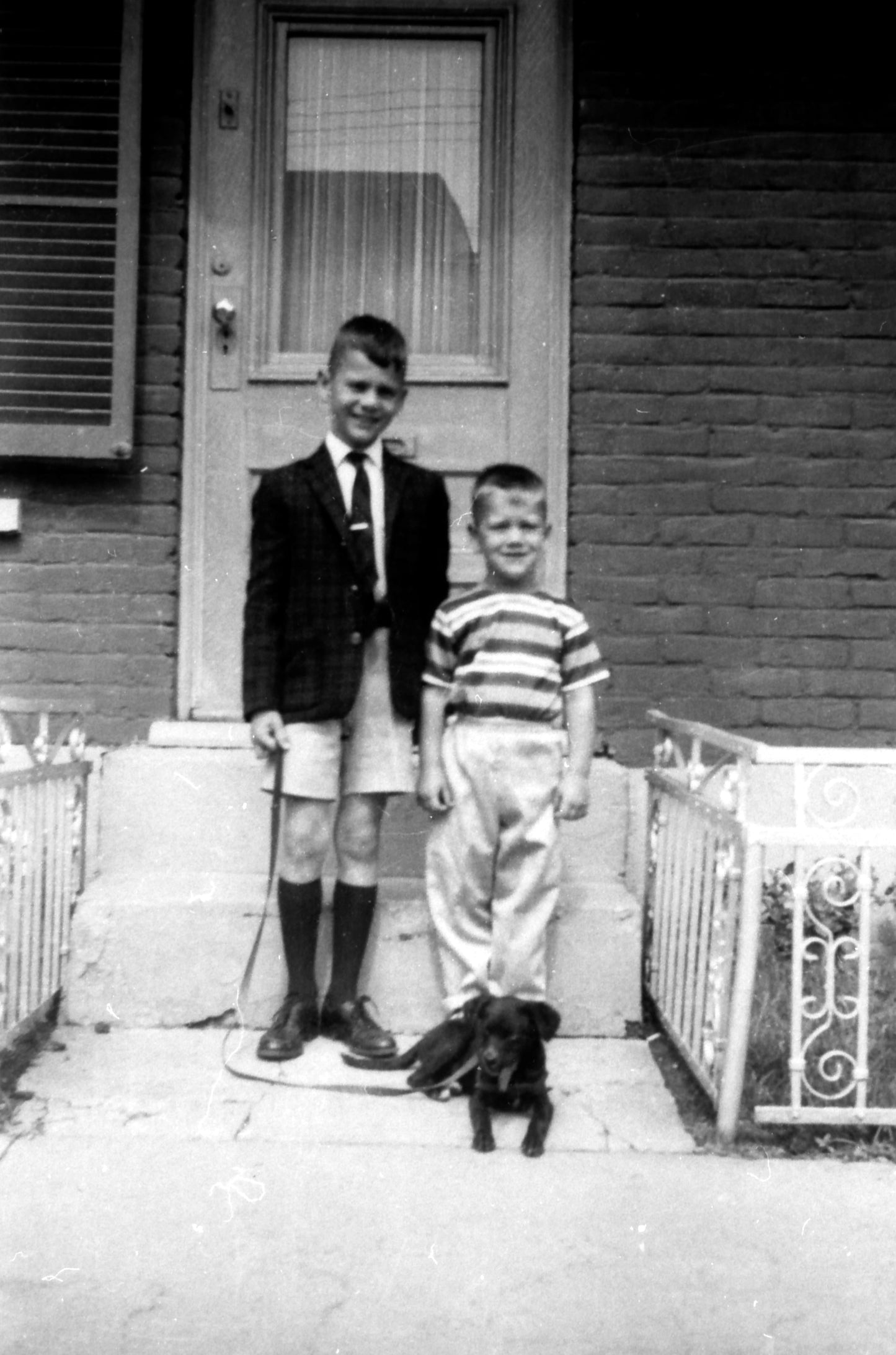 Deux enfants et un chien devant une maison